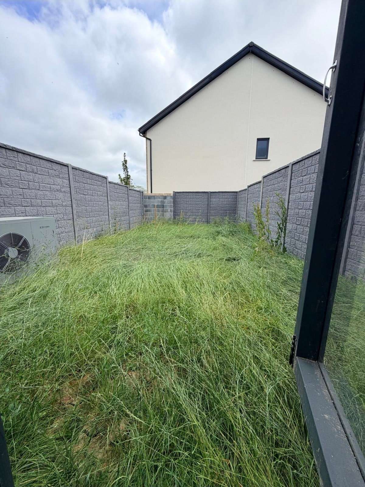 Before: an overgrown back garden with long grass and weeds